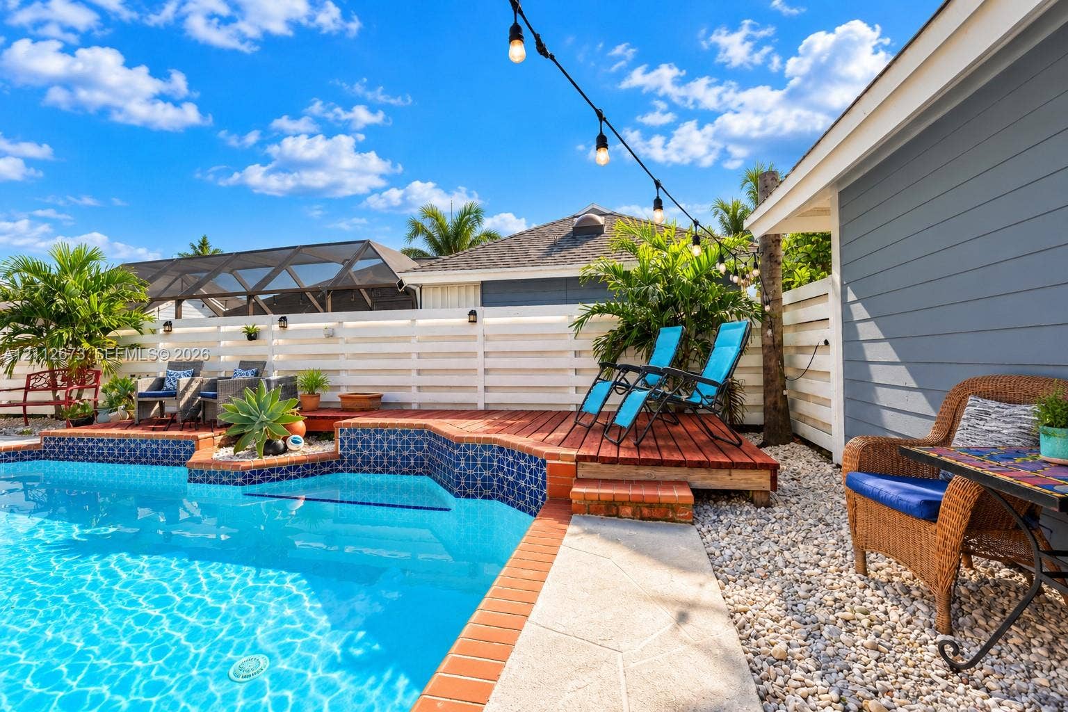 10225 SW 141st Court, #0, Miami, Miami, FL 33186 In-ground swimming pool with patterned tile border, raised wood decking, horizontal slat fencing, and stone landscape ground cover