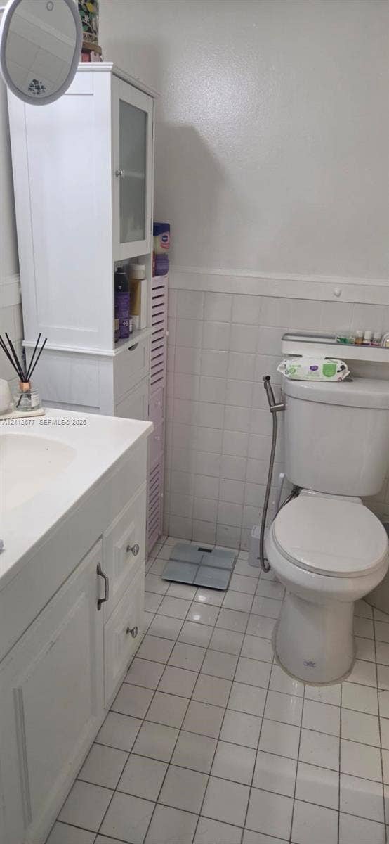 6675 W 4th Avenue, #206, Hialeah, FL 33012 Bathroom featuring white cabinetry, a built-in vertical storage tower, square-tile flooring, tiled wainscoting, and a standard-height toilet