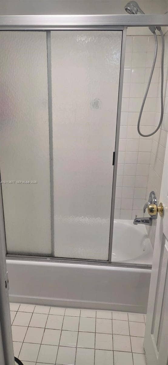 6675 W 4th Avenue, #206, Hialeah, FL 33012 Bathtub and shower combination featuring a sliding glass enclosure, white ceramic wall tile, and a handheld shower fixture