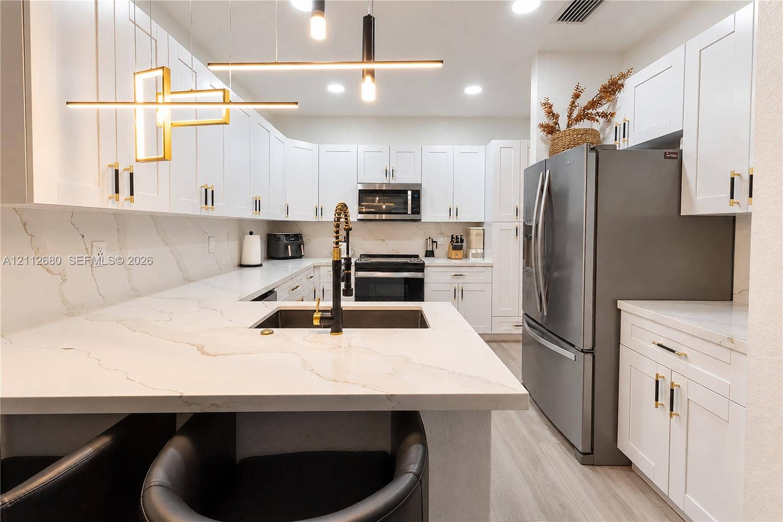 890 SW 154th Path, Miami, FL 33194 Kitchen featuring white shaker-style cabinetry, white countertops with grey veining, integrated stainless steel appliances, a pull-down faucet, and contemporary geometric pendant lighting