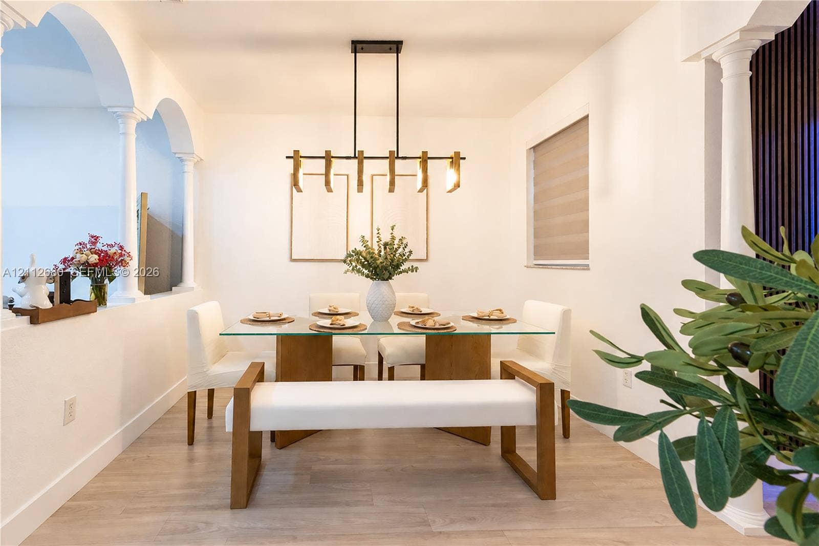 890 SW 154th Path, Miami, FL 33194 Dining area featuring structural architectural columns, decorative interior archways, wood-finish flooring, and a linear pendant light fixture