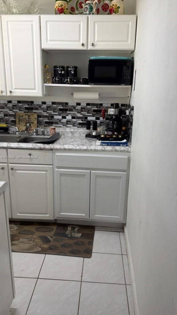 1655 W 44th Place, #435, Hialeah, FL 33012 Kitchen featuring white cabinetry, stone-patterned laminate countertops, and a multi-toned mosaic tile backsplash