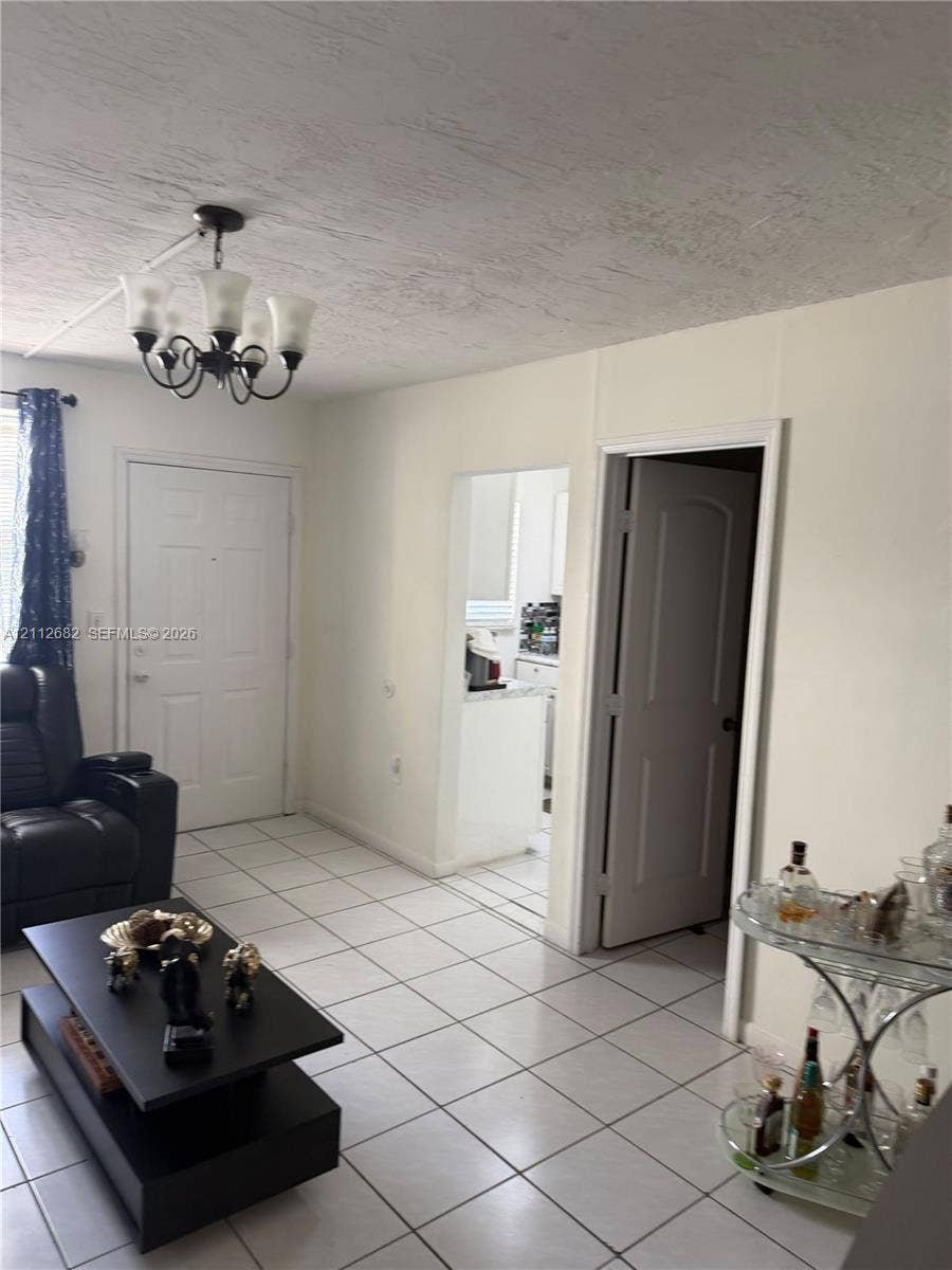 1655 W 44th Place, #435, Hialeah, FL 33012 Interior featuring large-format ceramic tile flooring, five-light iron chandelier, and neutral wall tones
