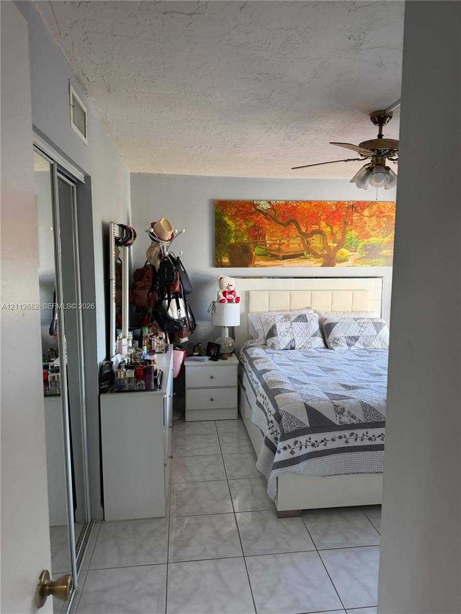 1655 W 44th Place, #435, Hialeah, FL 33012 Room featuring light-toned tile flooring, dual sliding-mirror closet doors, and a ceiling fan with integrated lighting