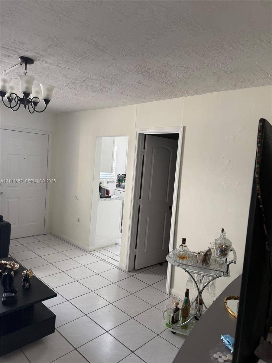 1655 W 44th Place, #435, Hialeah, FL 33012 Interior space featuring tile flooring, six-panel interior doors, and a decorative multi-arm chandelier