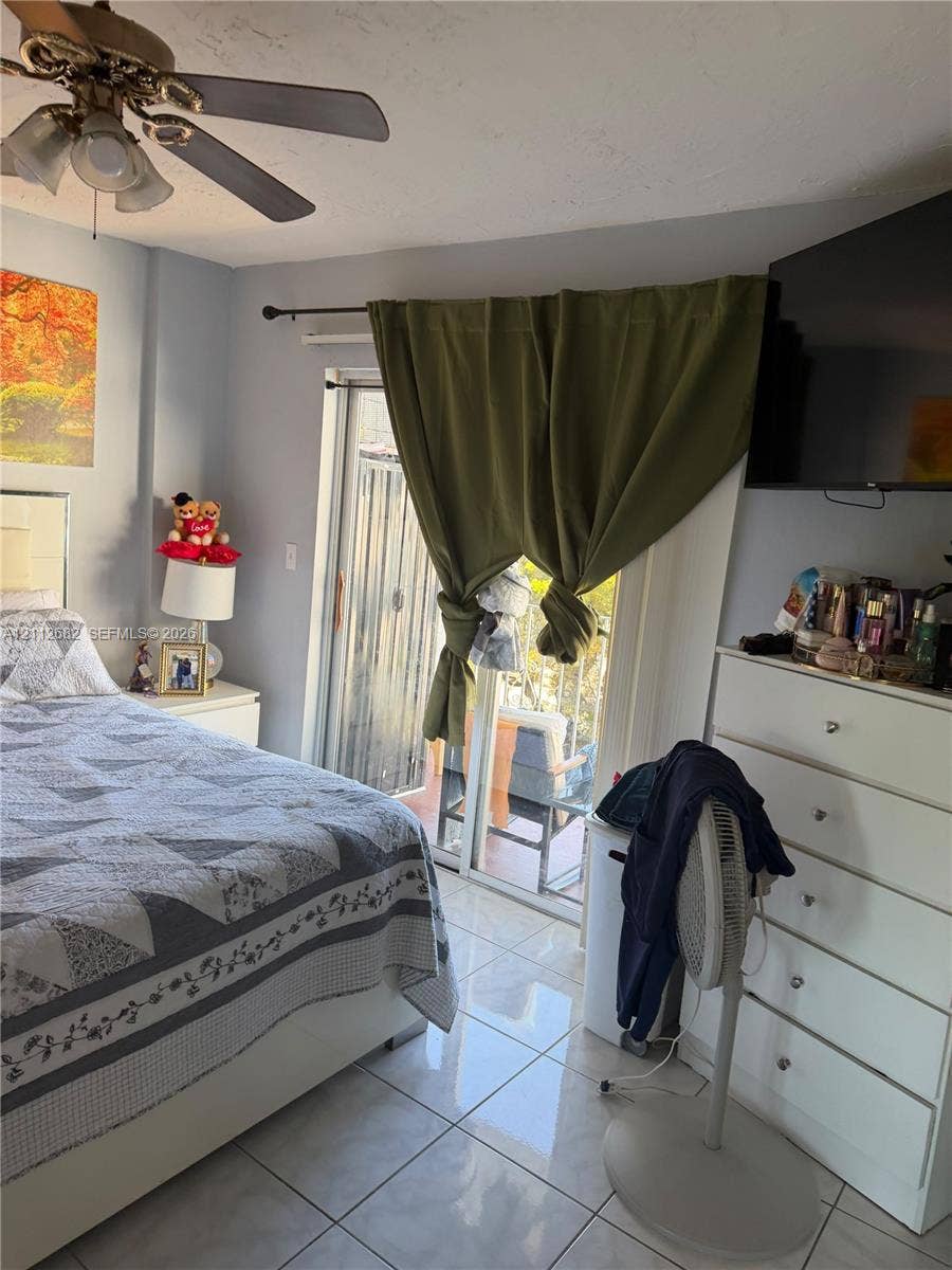 1655 W 44th Place, #435, Hialeah, FL 33012 Sliding glass door, neutral tile flooring, and ceiling fan with integrated light fixture