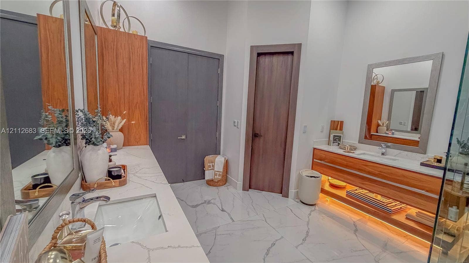 Dual-vanity bathroom featuring stone-look flooring, floating wood cabinetry, quartz countertops, rectangular undermount sinks, and integrated under-cabinet lighting