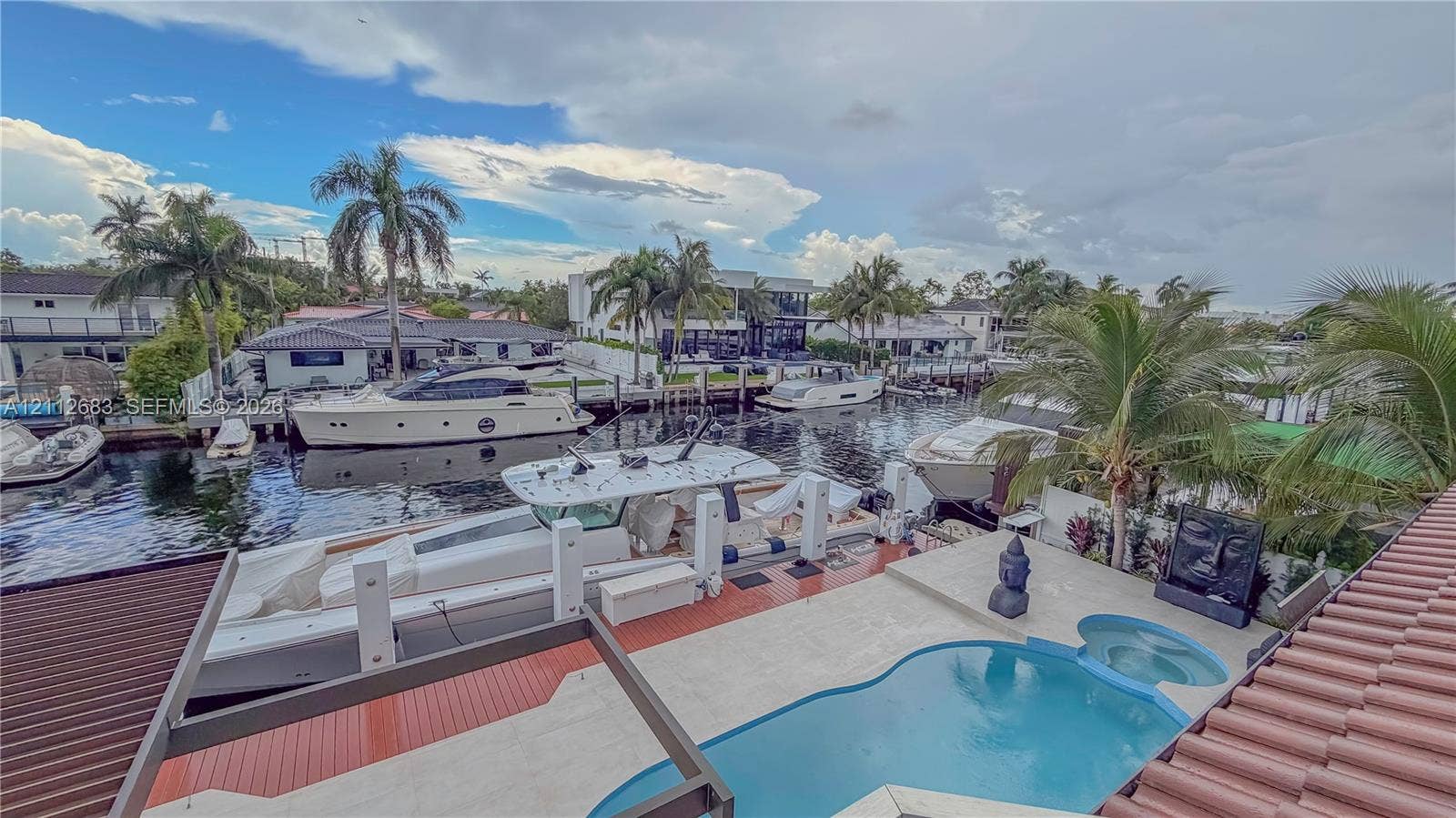 Waterfront patio featuring a custom-shaped swimming pool, integrated spa, and boat dock with pilings