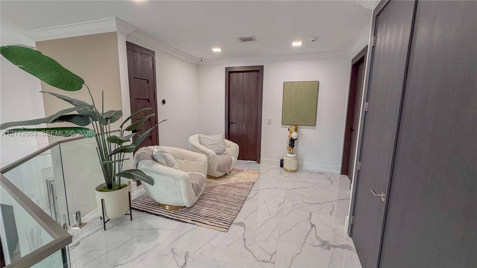 Interior space featuring large-format tile flooring with marble-style veining, recessed lighting, crown molding, and high-contrast dark wood-finish interior doors