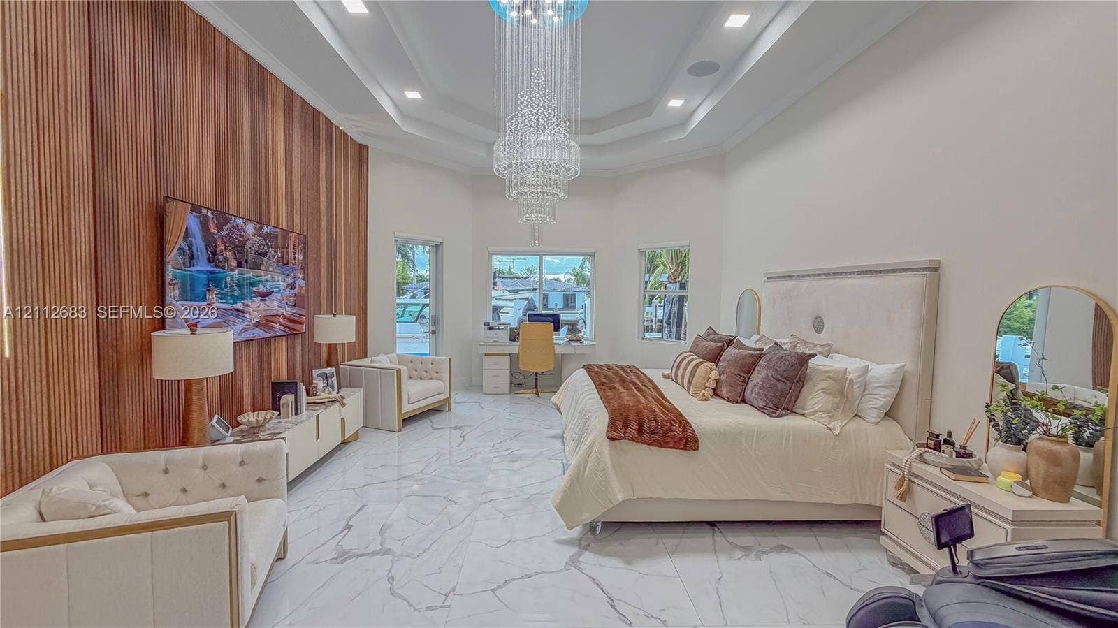 Interior space featuring a vaulted ceiling with recessed lighting, a multi-tiered crystal chandelier, stone-finish tile flooring, and a vertical wood-slat accent wall