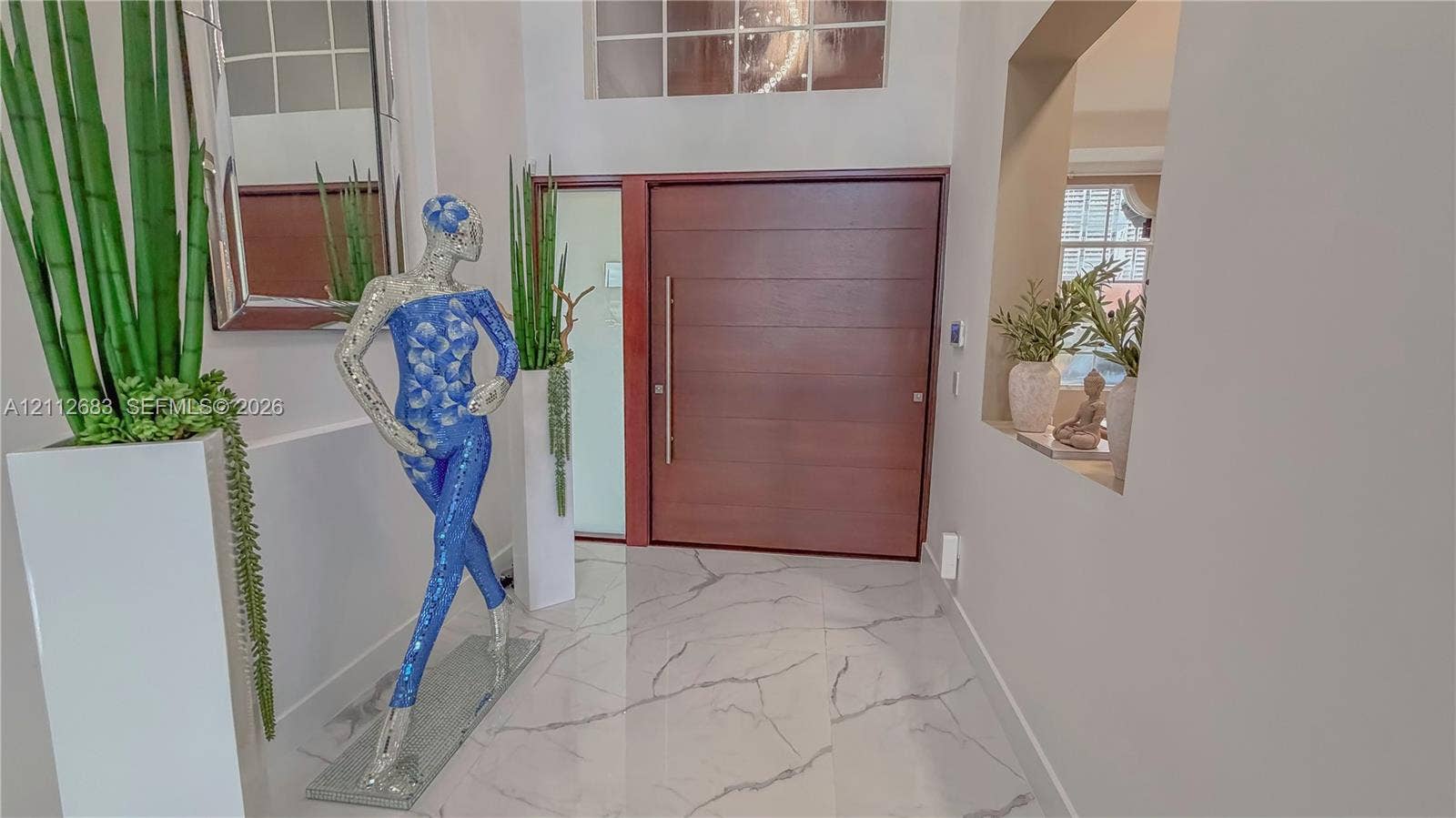 Entryway featuring polished stone-finish flooring, a contemporary horizontal-panel wood door with a vertical tubular handle, a side-lite panel, and an overhead transom window