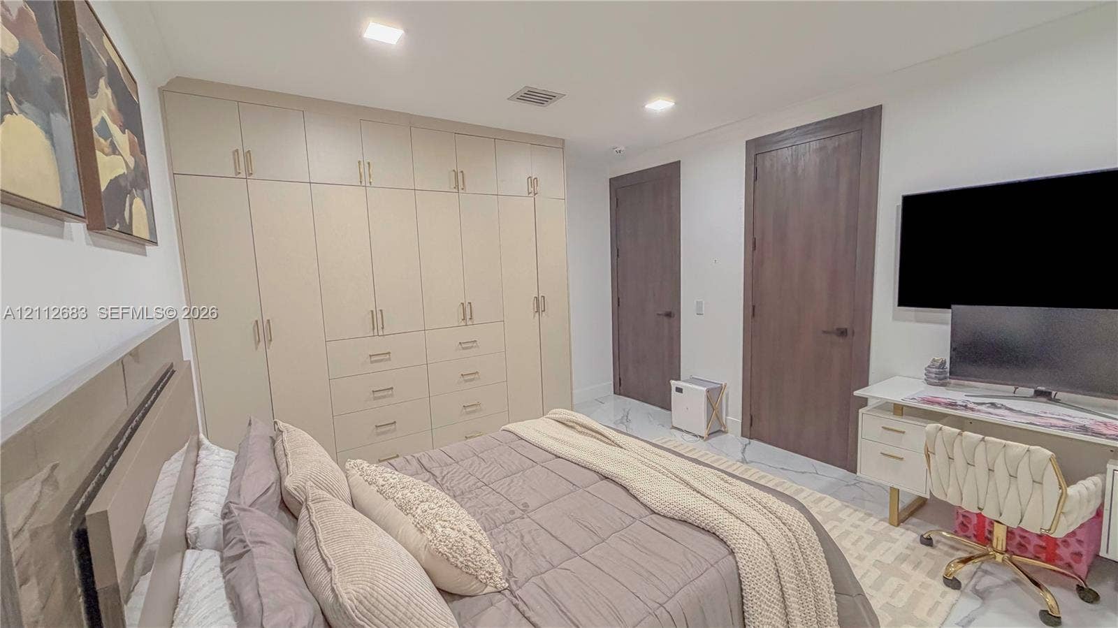 Custom floor-to-ceiling built-in cabinetry featuring integrated drawer storage, contrasting dark-stained wood doors, recessed ceiling lighting, and polished stone-finish flooring