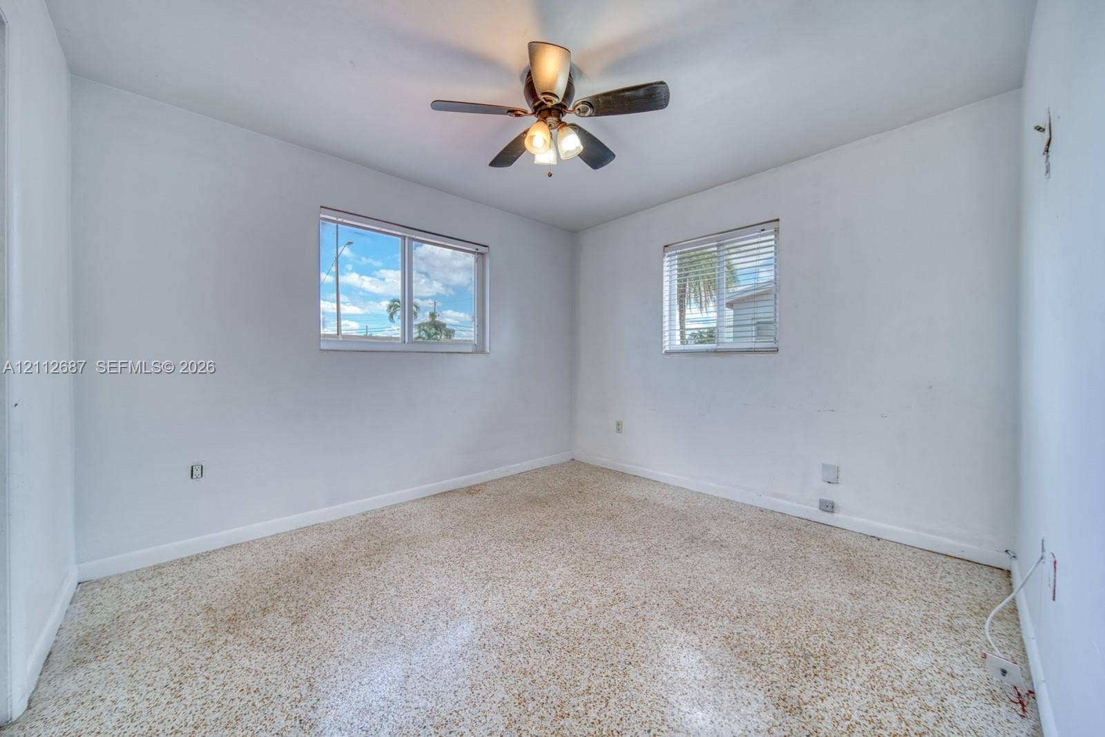 9340 SW 26th Street, Miami, FL 33165 Neutral-toned terrazzo flooring, two windows with horizontal blinds, and a central ceiling fan with multi-light fixture