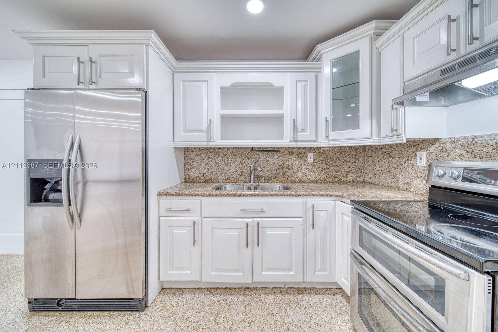 9340 SW 26th Street, Miami, FL 33165 Kitchen featuring white shaker-style cabinetry, stone-finish countertops, stainless steel appliances, glass-front upper cabinet, and double-basin undermount sink