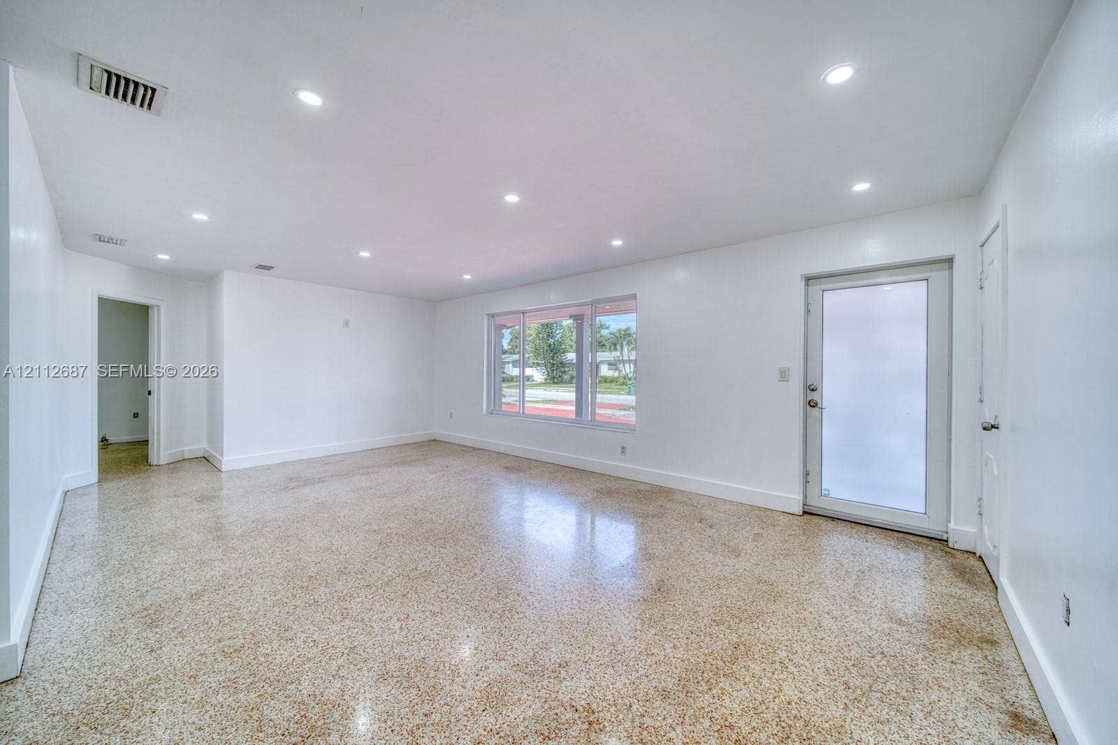 9340 SW 26th Street, Miami, FL 33165 Spacious room featuring polished terrazzo flooring, recessed lighting, and a glass-paneled exterior door