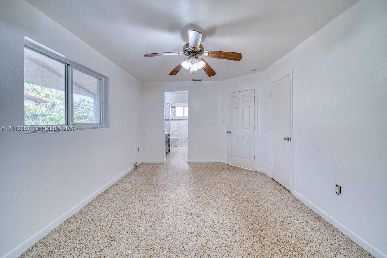 9340 SW 26th Street, Miami, FL 33165 Interior space featuring neutral wall paint, terrazzo flooring, a ceiling fan with integrated lighting, and two six-panel interior doors