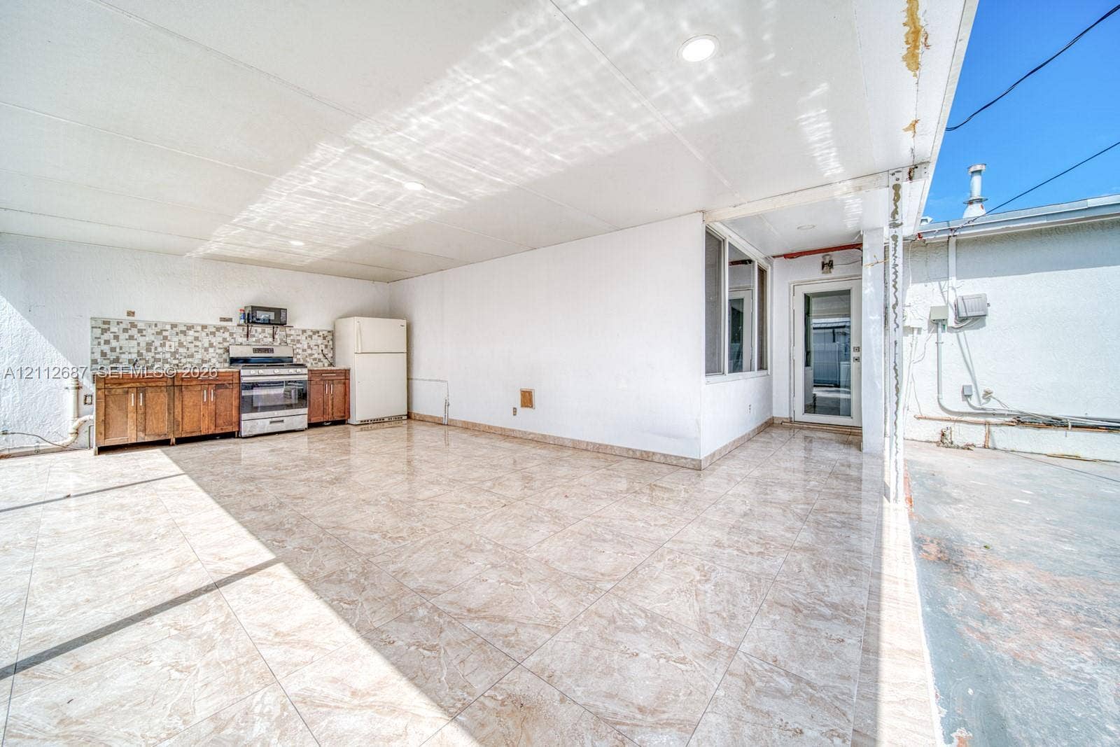 9340 SW 26th Street, Miami, FL 33165 Covered outdoor area featuring tile flooring, built-in cabinetry, a stone-patterned backsplash, and recessed lighting