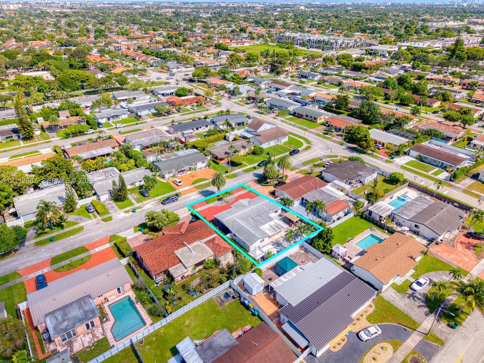 9340 SW 26th Street, Miami, FL 33165 Aerial perspective featuring a single-story residence with a multi-hipped roof, paved driveway, enclosed backyard, and mature landscaping