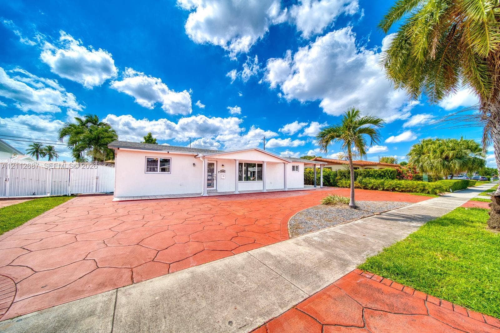 9340 SW 26th Street, Miami, FL 33165 Single-story exterior featuring white stucco siding, expansive stamped concrete driveway, and mature landscaping