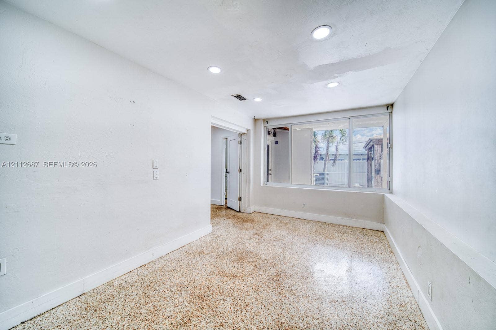 9340 SW 26th Street, Miami, FL 33165 Interior space featuring terrazzo flooring, recessed ceiling lighting, and a multi-panel sliding window