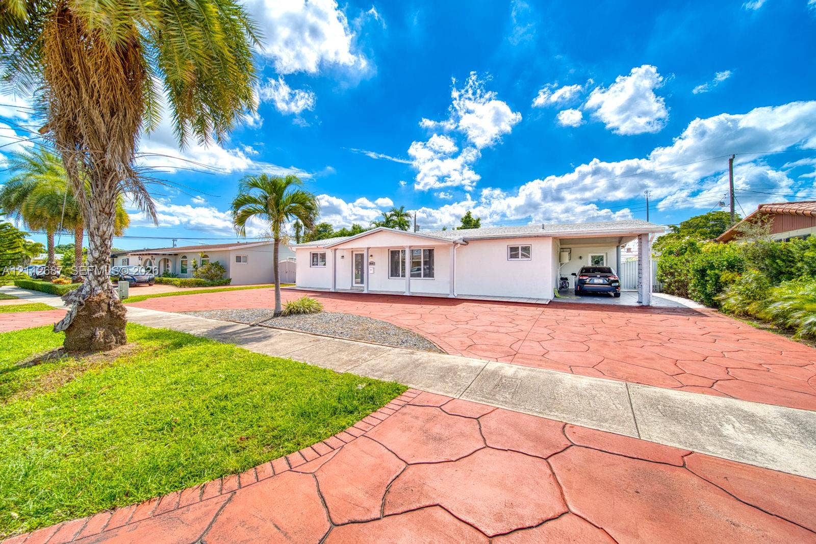 9340 SW 26th Street, Miami, FL 33165 Single-story exterior featuring white stucco siding, a covered carport, and extensive stamped concrete driveway