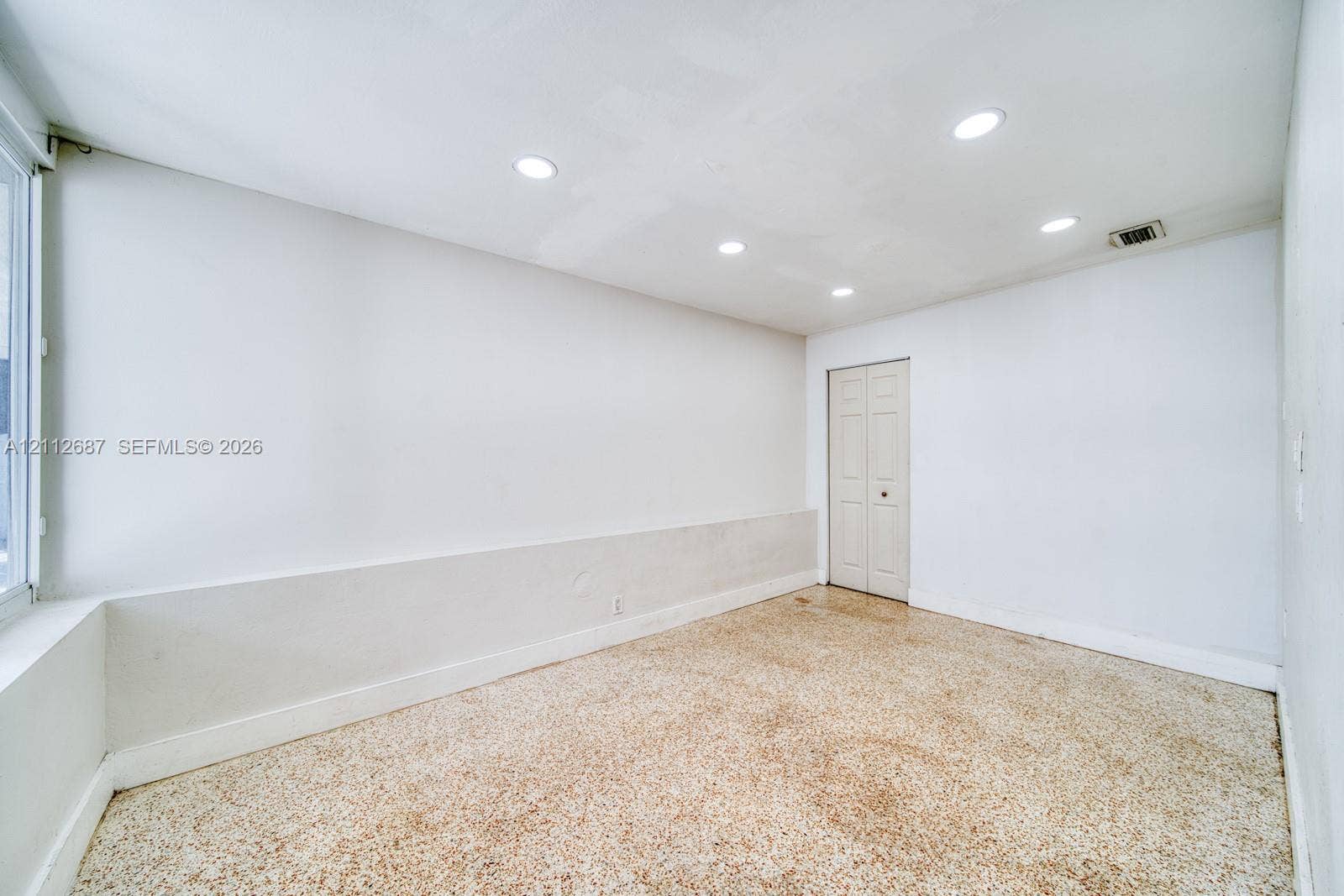 9340 SW 26th Street, Miami, FL 33165 Neutral-toned room featuring recessed ceiling lighting, a bi-fold closet door, and patterned resilient flooring