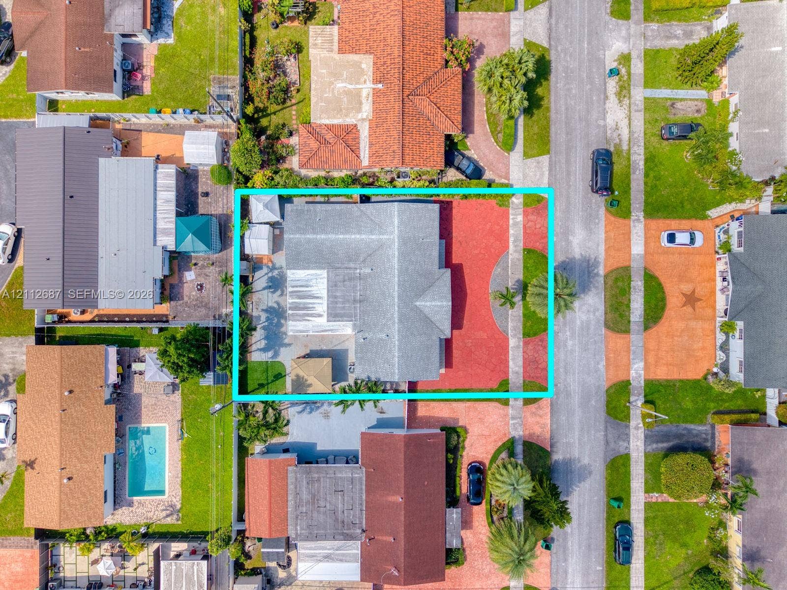 9340 SW 26th Street, Miami, FL 33165 Aerial view featuring a shingle roof, paved driveway, expansive red-toned hardscaping, and a rectangular lot configuration