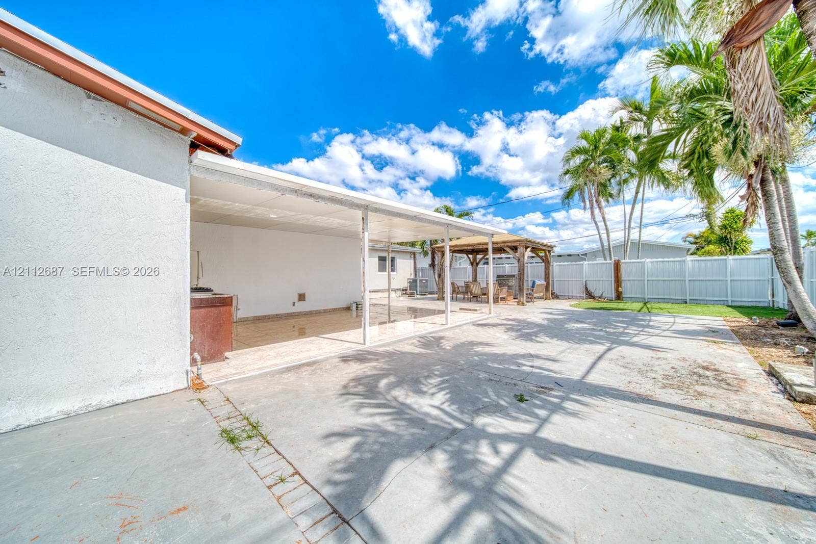 9340 SW 26th Street, Miami, FL 33165 Expansive concrete patio featuring a covered lanai, built-in outdoor kitchen station, freestanding gazebo, and full perimeter privacy fencing