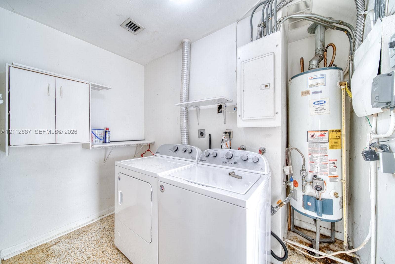 9340 SW 26th Street, Miami, FL 33165 Utility area featuring white wall-mounted cabinetry, integrated open shelving, and a dedicated tank-style water heater