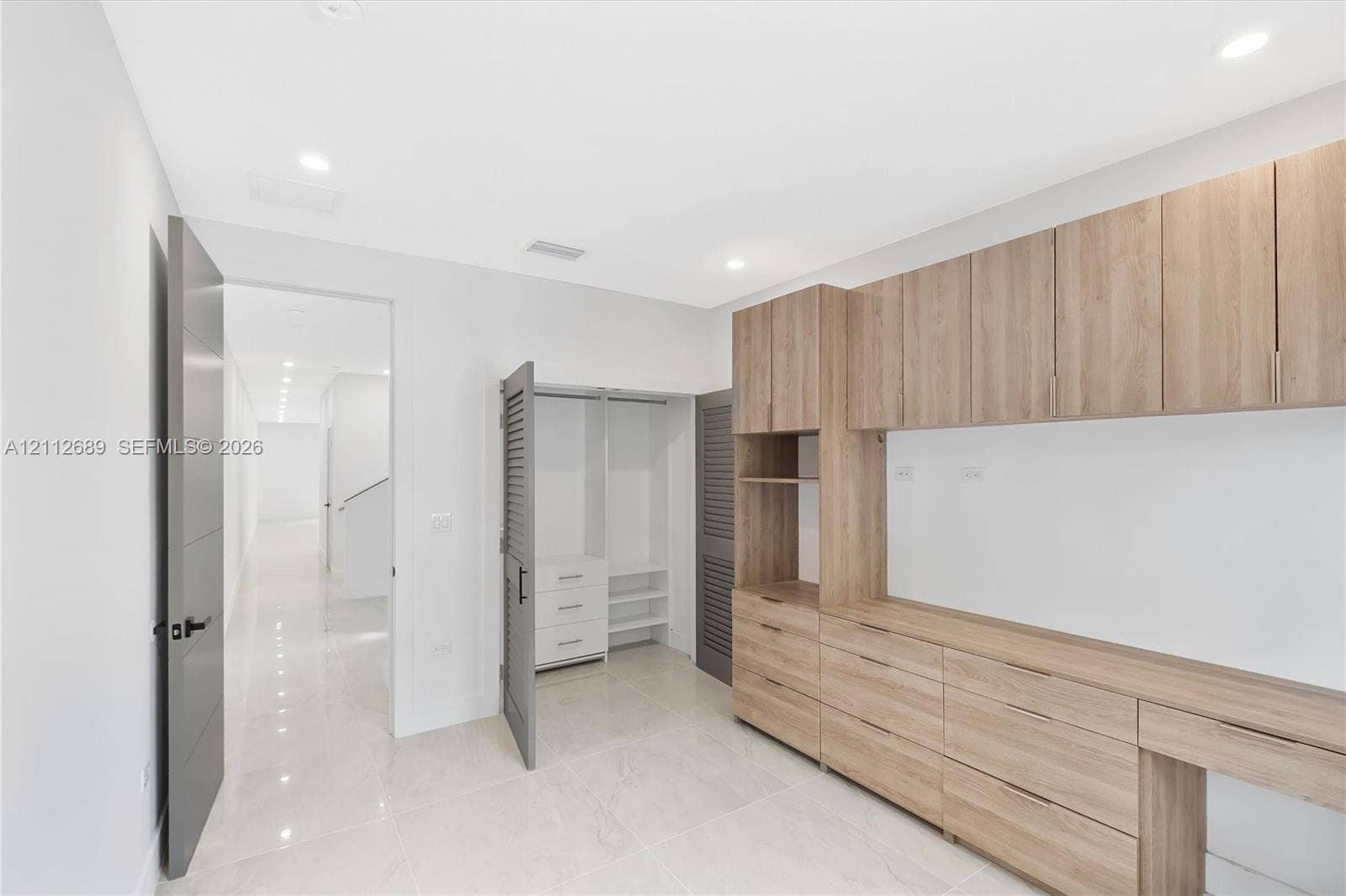 2889 SW 33rd Avenue, #2889, Miami, Miami, FL 33133 Custom wood-finish built-in cabinetry, integrated desk workspace, recessed lighting, polished tile flooring, and louvered-door closet