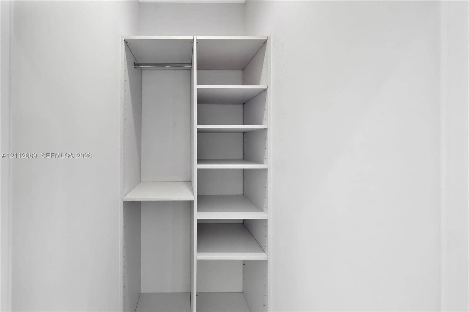 2889 SW 33rd Avenue, #2889, Miami, Miami, FL 33133 Built-in closet system featuring white shelving, adjustable rack pinholes, and a metal hanging rod