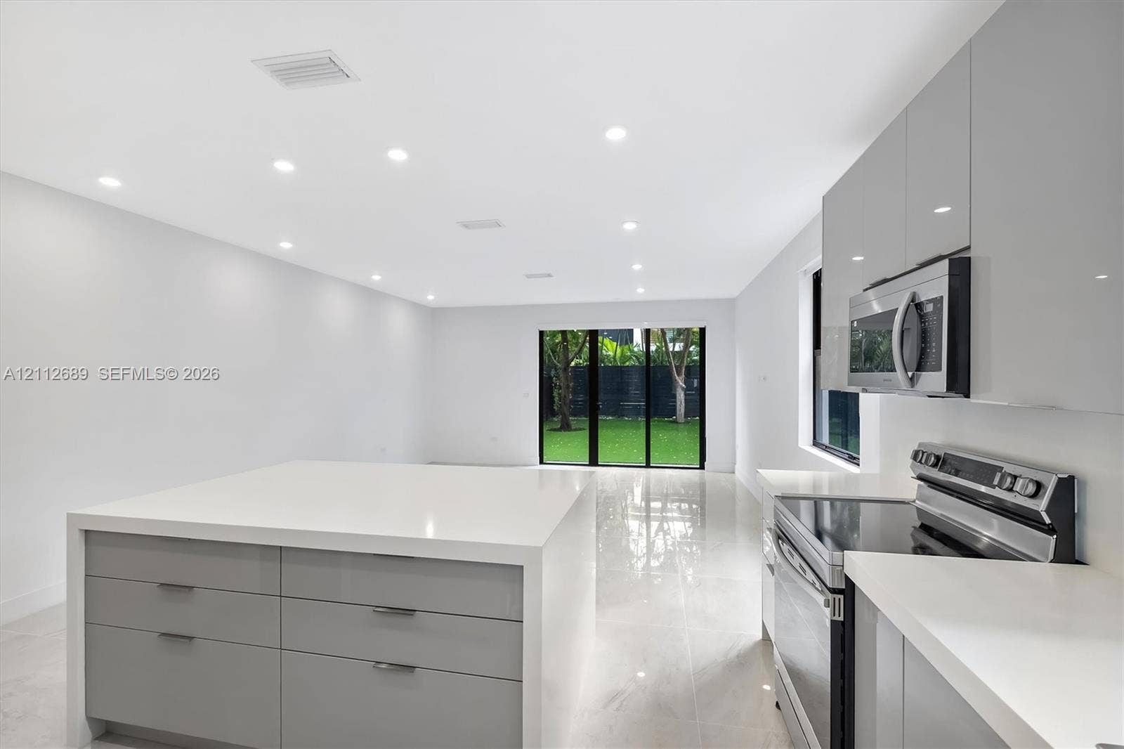 2889 SW 33rd Avenue, #2889, Miami, Miami, FL 33133 Modern kitchen featuring high-gloss cabinetry, stone-surface waterfall island, stainless steel appliances, recessed ceiling lighting, and polished tile flooring