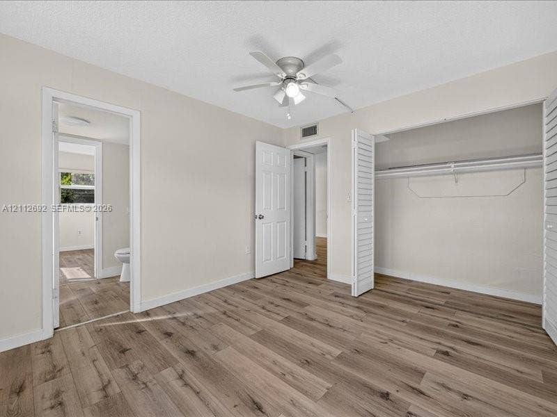 1111 NW 19th Avenue, #205, Miami, FL 33125 Room featuring wood-finish flooring, a ceiling fan with integrated lighting, and a closet with bifold louvered doors