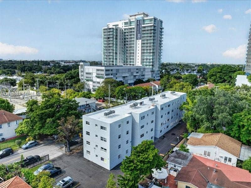 1111 NW 19th Avenue, #205, Miami, FL 33125 Multi-story residential building featuring a flat roofline, neutral exterior cladding, and dedicated surface parking