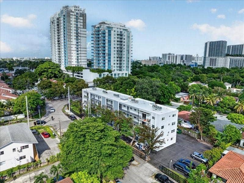 1111 NW 19th Avenue, #205, Miami, FL 33125 Multi-story residential building featuring a white facade, private balconies, and dedicated asphalt surface parking