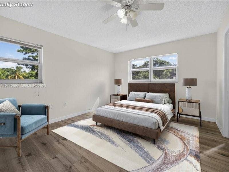 1111 NW 19th Avenue, #205, Miami, FL 33125 Wood-finish flooring, dual windows with exterior foliage, and a ceiling-mounted light fixture with fan