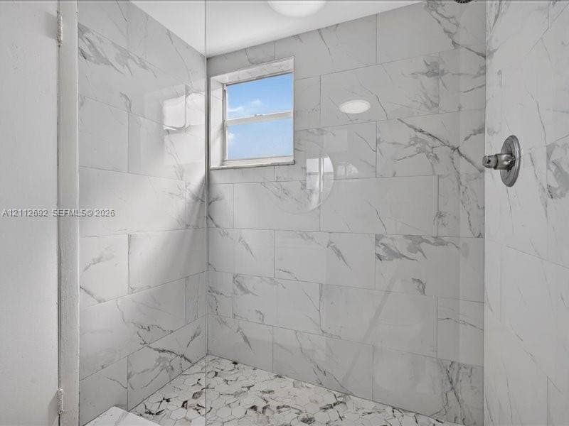 1111 NW 19th Avenue, #205, Miami, FL 33125 Walk-in shower featuring large-format porcelain wall tile, hexagonal floor tile, a recessed window, and a wall-mounted faucet fixture
