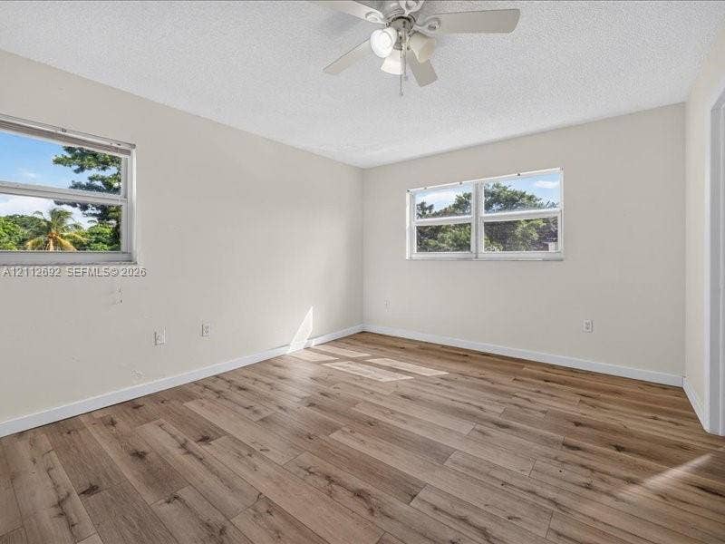 1111 NW 19th Avenue, #205, Miami, FL 33125 Neutral-toned interior space featuring wood-finish flooring, dual windows, and a ceiling-mounted light fixture with fan