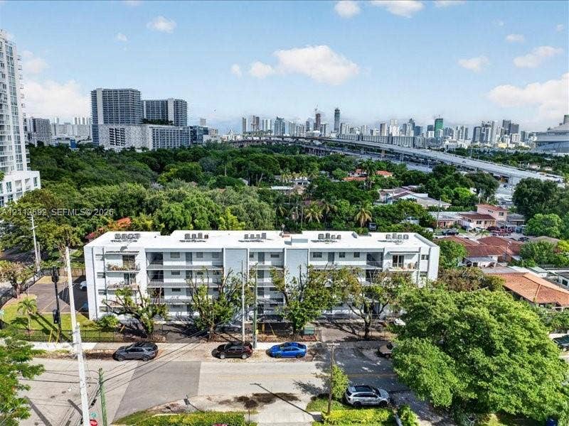 1111 NW 19th Avenue, #205, Miami, FL 33125 Multi-story residential building featuring a flat roofline, neutral exterior cladding, integrated recessed balconies, and dedicated surface parking
