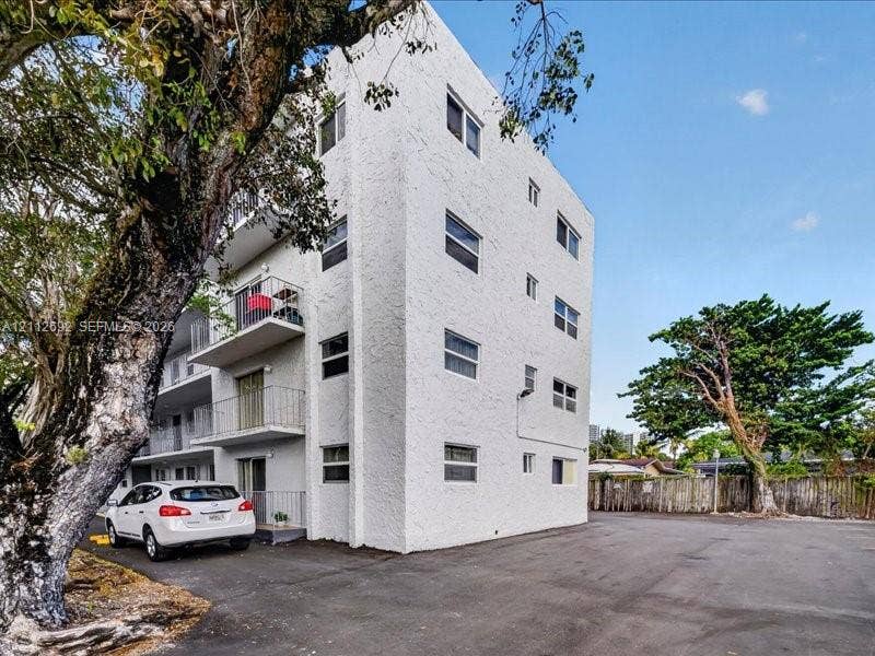 1111 NW 19th Avenue, #205, Miami, FL 33125 Multi-story stucco exterior featuring private balconies with metal railings and paved surface parking