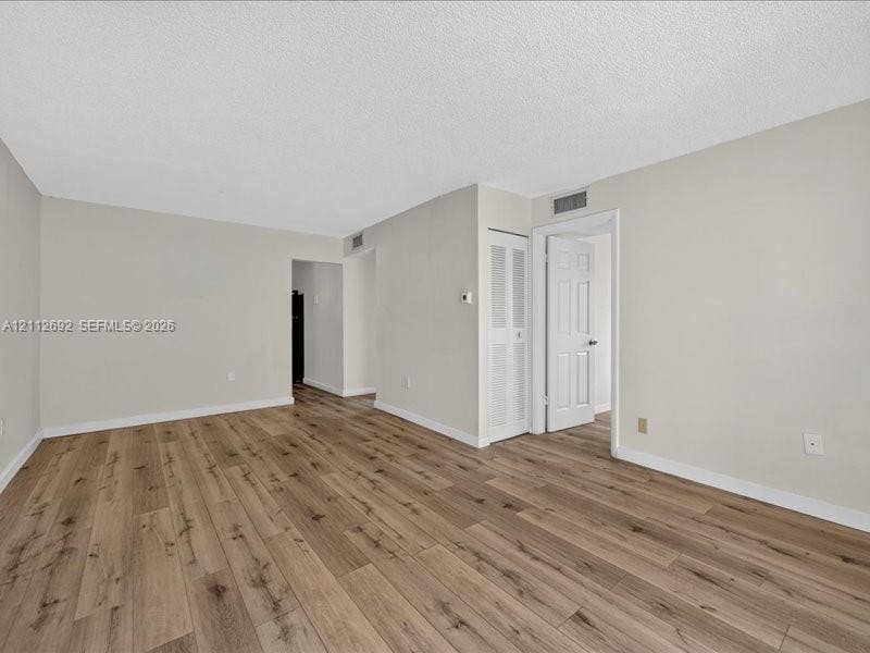 1111 NW 19th Avenue, #205, Miami, FL 33125 Interior space featuring wood-finish flooring, neutral wall tones, and a six-panel interior door