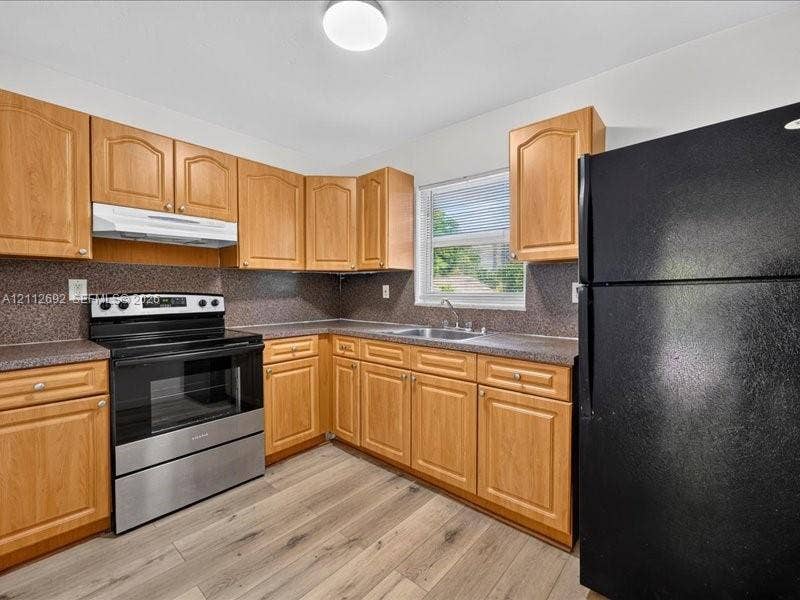 1111 NW 19th Avenue, #205, Miami, FL 33125 Kitchen featuring wood cabinetry, stone-composite countertops, stainless steel range with overhead hood, and wood-finish flooring