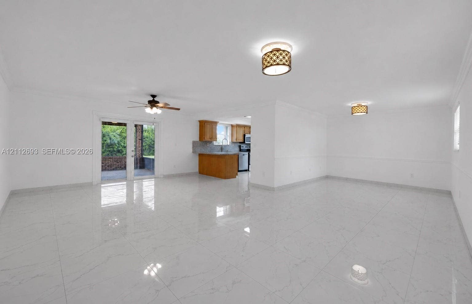 Homestead, Homestead, FL 33033 Open-concept interior featuring large-format tile flooring, double glass doors, ceiling fan, and decorative flush-mount lighting fixtures