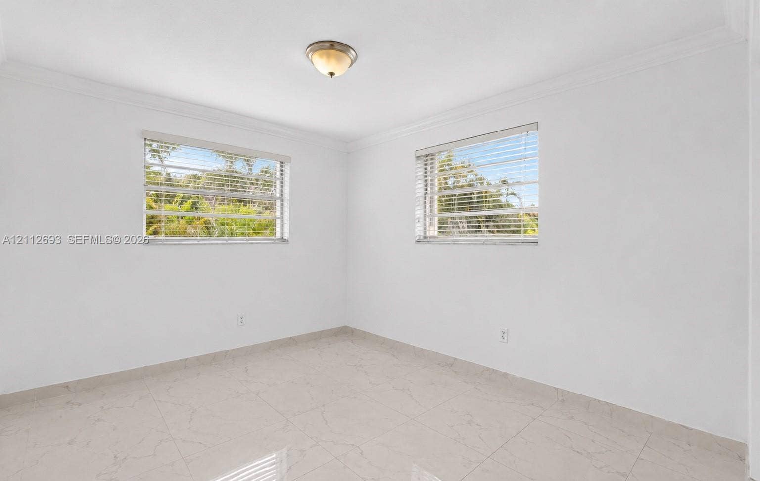 Homestead, Homestead, FL 33033 Neutral-toned tile flooring, white walls, crown molding, two windows with horizontal blinds, and a semi-flush mount ceiling fixture