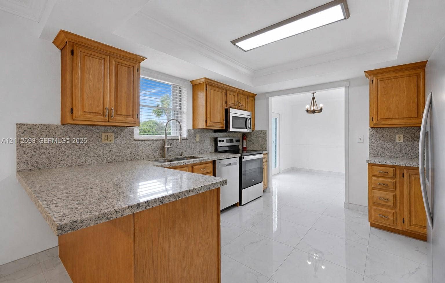 Homestead, Homestead, FL 33033 Kitchen featuring wood cabinetry, stone countertops, stone backsplash, stainless steel appliances, and large-format tile flooring