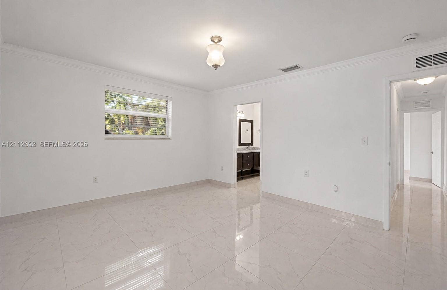 Homestead, Homestead, FL 33033 Interior space featuring polished light-toned tile flooring, crown molding, a central glass-shaded light fixture, and a horizontal window