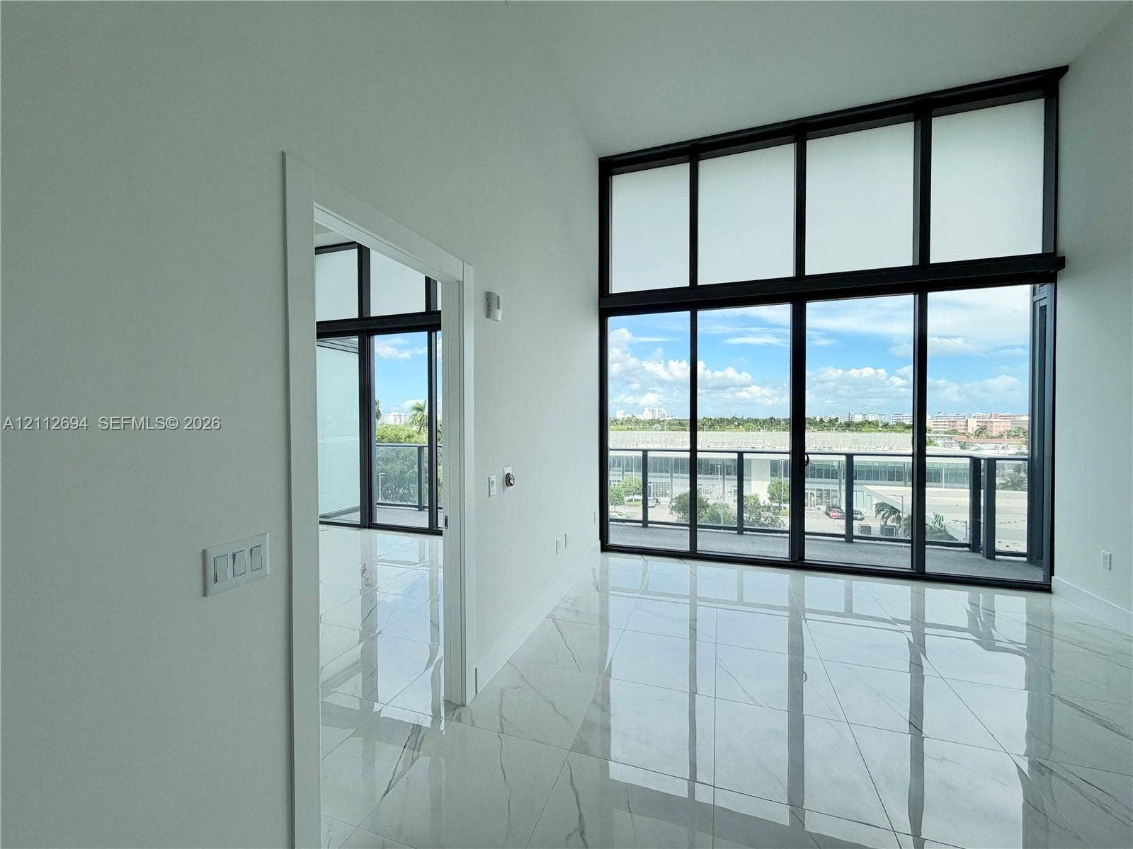 1170 E Hallandale Beach Boulevard, #503, Hallandale Beach, Hallandale Beach, FL 33009 Floor-to-ceiling windows with dark framing, large-format stone-finish tile flooring, and sliding glass doors with access to a railed balcony