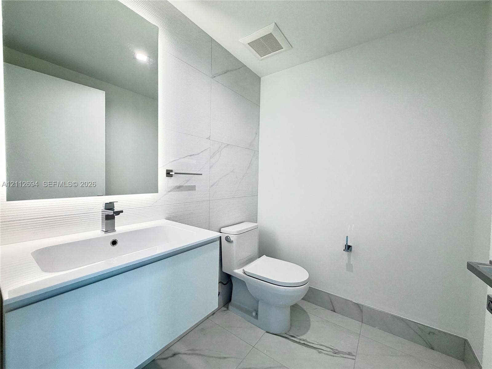1170 E Hallandale Beach Boulevard, #503, Hallandale Beach, Hallandale Beach, FL 33009 Floating vanity with a rectangular sink, integrated LED mirror, large-format stone-patterned wall tile, and polished metal faucet