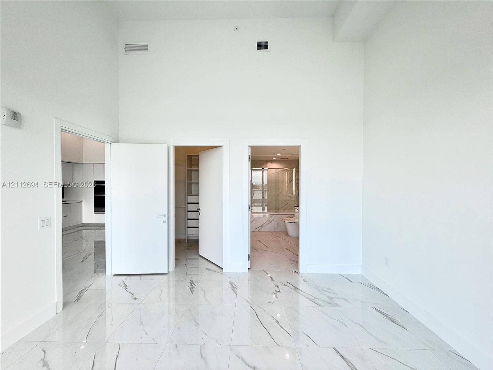 1170 E Hallandale Beach Boulevard, #503, Hallandale Beach, Hallandale Beach, FL 33009 High-ceiling interior featuring polished, large-format stone-patterned tile flooring, minimalist white solid-core doors, and built-in closet shelving