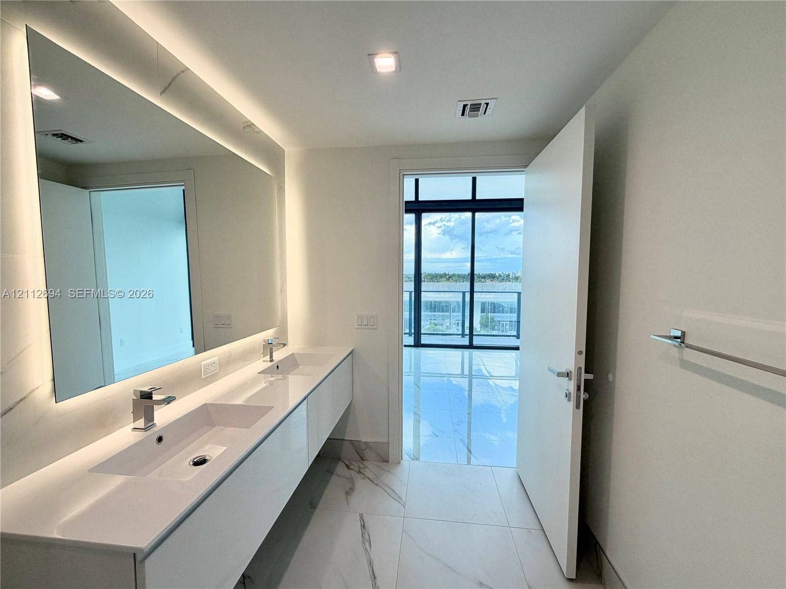 1170 E Hallandale Beach Boulevard, #503, Hallandale Beach, Hallandale Beach, FL 33009 Modern floating vanity with dual integrated sinks, quartz countertop, large backlit mirror, and floor-to-ceiling stone-finish tile flooring